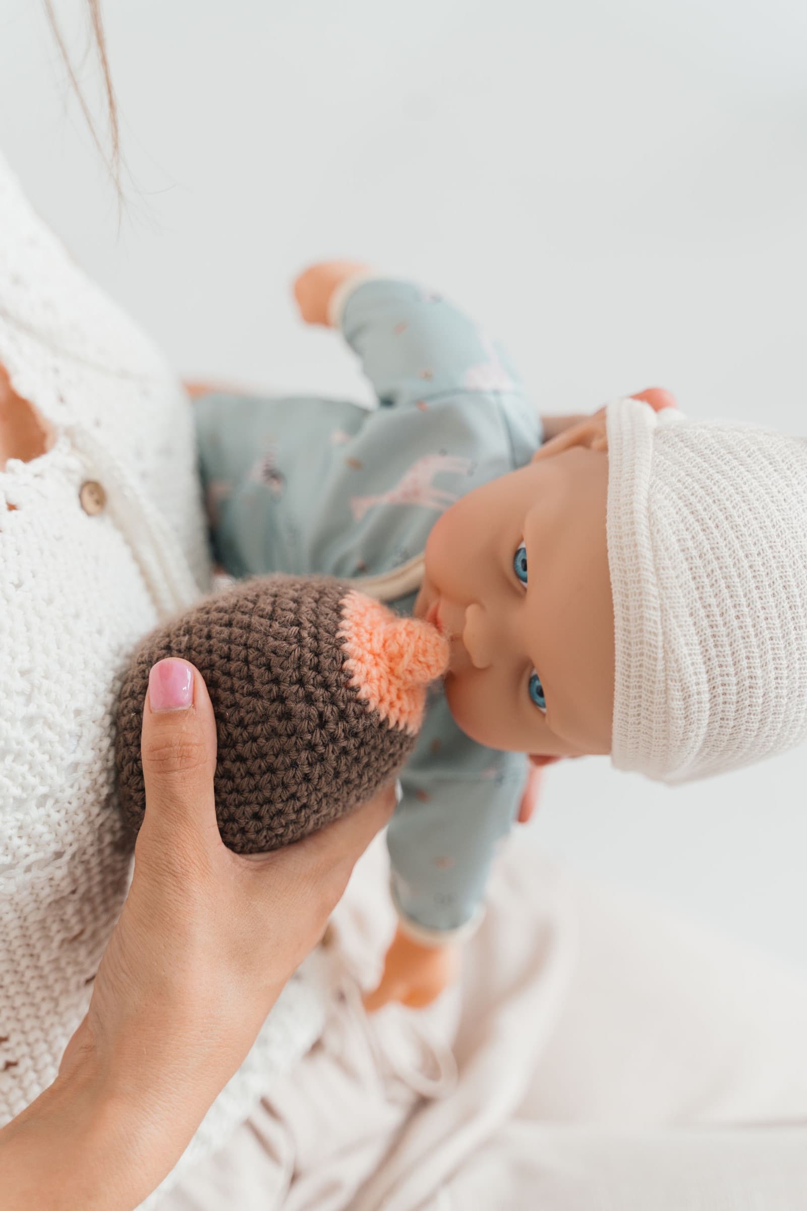 Hands holding a newborn doll in pyjamas — preparing for the postnatal period