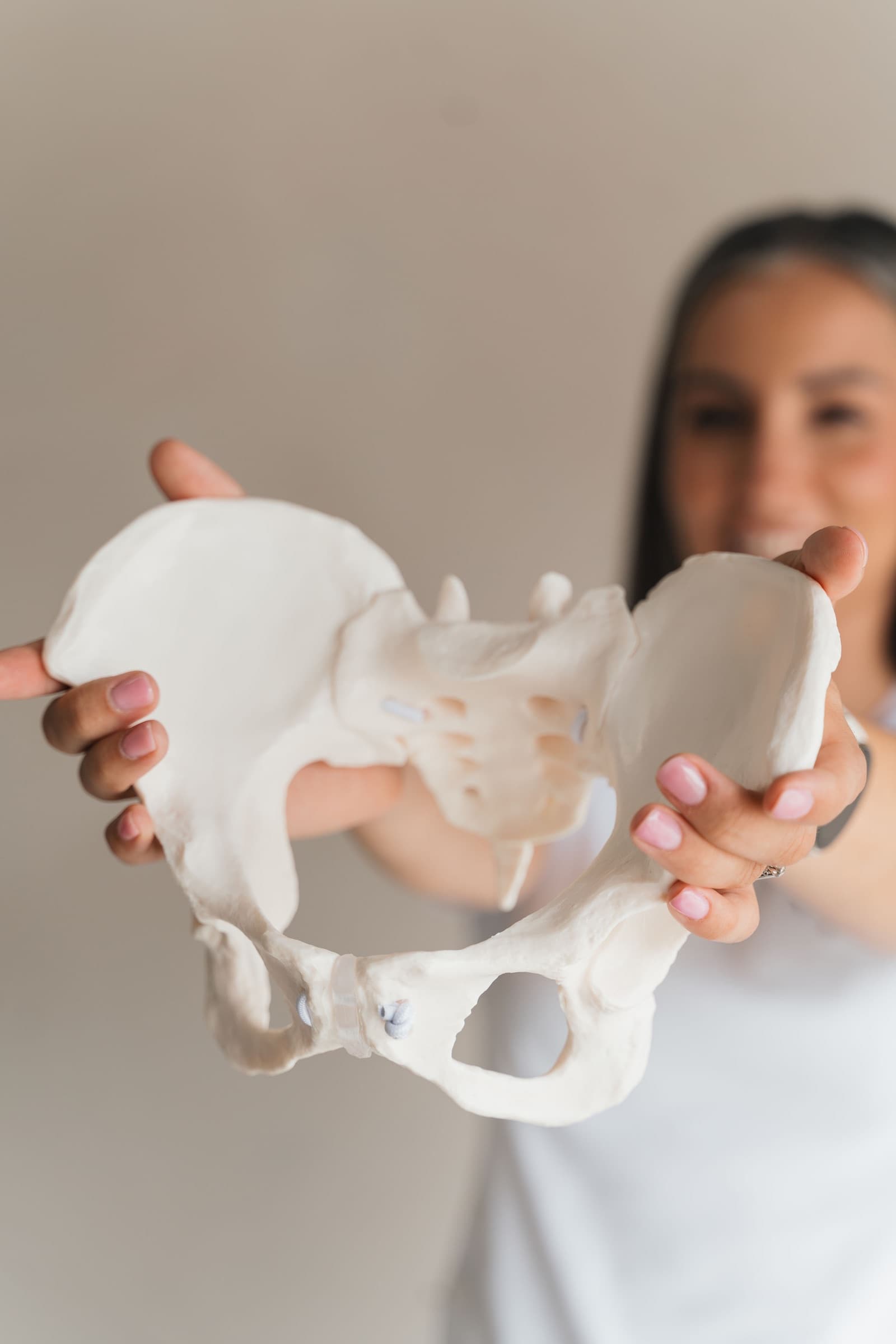 Leoni holding an anatomical pelvis model toward the camera